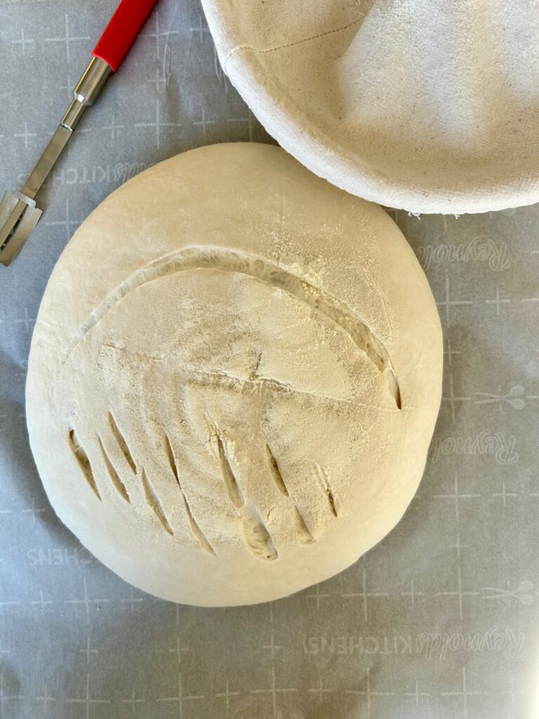 unclose shot of scored unbaked sourdough bread on parchment paper